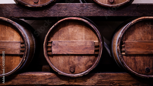 Photos Wooden barrels stored on a wooden rack in a winery for aging wine and fermentati
