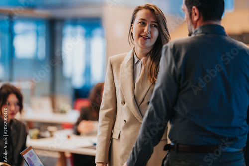 Foto A female and male colleague chat in a modern open-plan office, exchanging a friendly smile