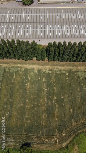 Canvastavla Industrial Landscape and Farmland: An aerial view captures a stark contrast between a large industrial complex with rows of parking spaces and a lush green agricultural field