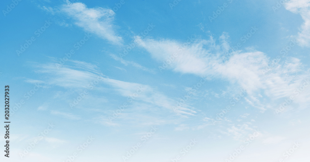 Fototapeta premium Soft clouds drift across a serene, light blue sky