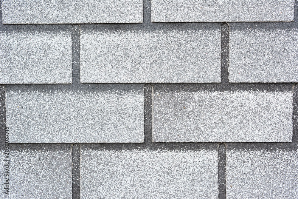 Fototapeta premium Close-up of gray asphalt roof shingles with granular texture