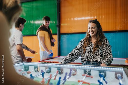 Cuadro en lienzo A group of friends play foosball and arcade games, smiling and enjoying themselves