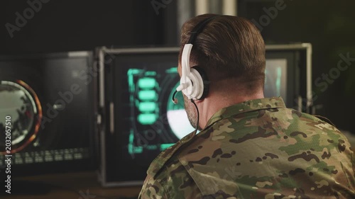 Middle-aged military officer in headset analyzing radar data for security threat