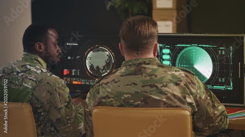 Two army officers discussing military operation while monitoring satellite data