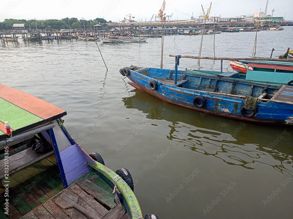 Obraz premium Traditional fishing boats at Lumpur Harbor with industrial factory background
