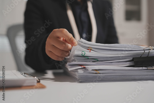 Foto Close-up of office worker handing over thick stack of paperwork with binder clip on desk, blurred background, corporate administration and bureaucracy concept