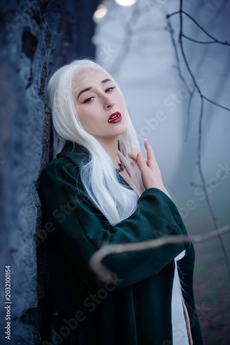 Gothic fantasy vampire woman in dark green cloak elegant portrait at twilight.