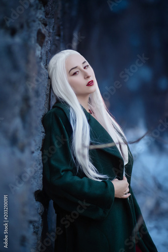 Gothic fantasy vampire woman in dark green cloak elegant portrait at twilight.