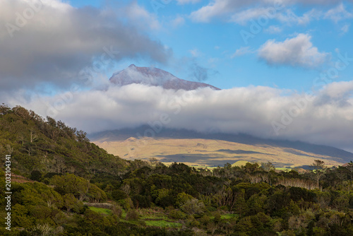 Pico Mountain stratovolcano surrounded by clouds and green forests on Pico Island, Azores, Portugal.