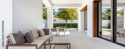 Modern covered patio featuring a sleek sofa, dining set and lush garden view. Bright, minimalist architecture for serene outdoor living, Outdoor Space, Contemporary