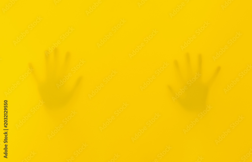 Obraz premium Silhouettes Of Hands And A Kid Behind Yellow Fabric