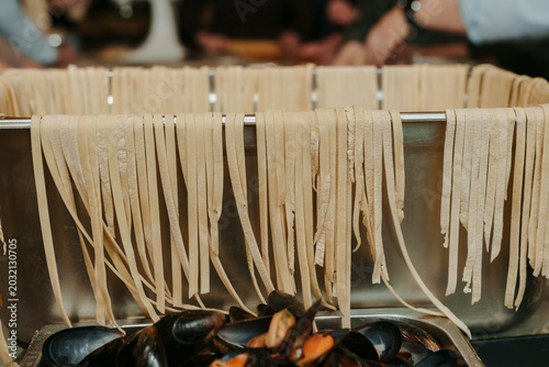 Foto Fresh handmade fettuccine drying over metal tray with fresh mussels