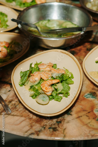 Fresh Caesar salad with grilled shrimps on a marble table.