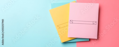 Vibrant flat lay Pastel pink, yellow and blue notebooks featuring minimalist blank banners, artfully arranged on a dual-tone bluepink background. Perfect for education or custom