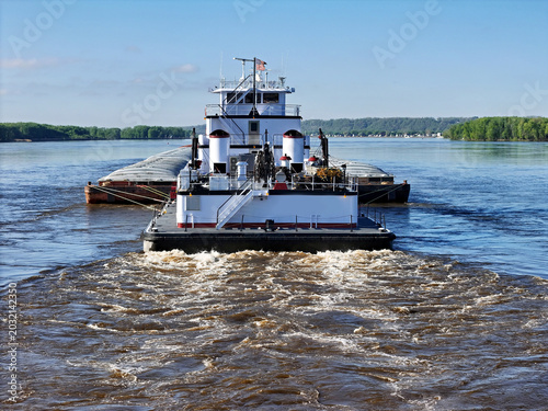 Rear view of a Tug boat pushing a large set of barges South down the Mississippi River