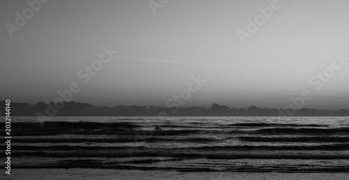 Konstfotografi Silhoutte of a lone surfer waiting for the perfect wave at dawn at Cocoa Beach i