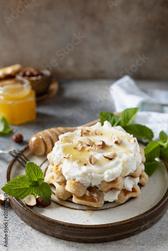 Belgian waffles with ricotta cheese, honey and hazelnuts for breakfast on a stone background. Sweet breakfast gluten free. Summer homemade recipe. Copy space.