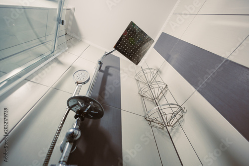 Photos Shower area with showerhead and storage shelves in modern bathroom during bright