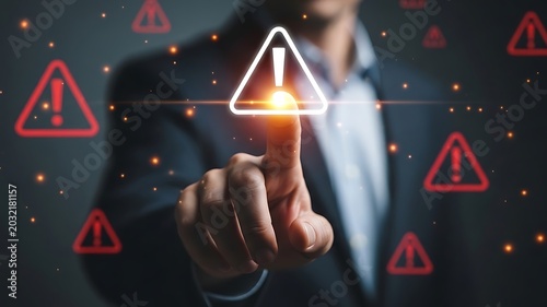 Man's finger touches glowing white exclamation mark in triangle warning symbol surrounded by red warning signs and orange sparks