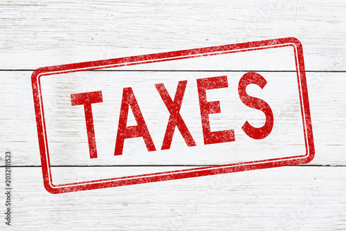 Red distressed Taxes stamp on weathered wood for taxation and IRS