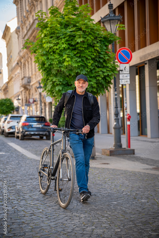 Fototapeta premium Confident bald man with his bicycle in the city