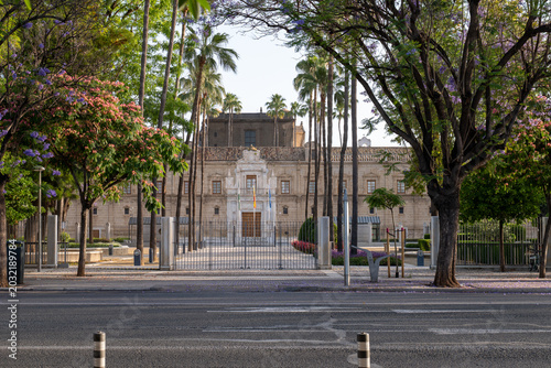 Parliament of Andalusia building facade behind trees and street in Seville Spain