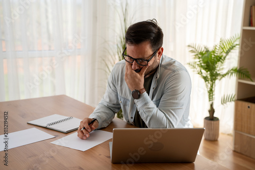 Fotografie Portrait of a casual entrepreneur looking at laptop at home office