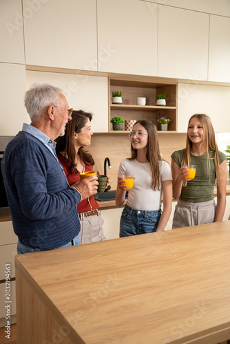 Happy multigeneration family talking and bonding during home kitchen gathering