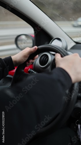 Vertical screen young man driving car through urban traffic realistic transportation lifestyle hands on steering wheel during everyday commute in modern city