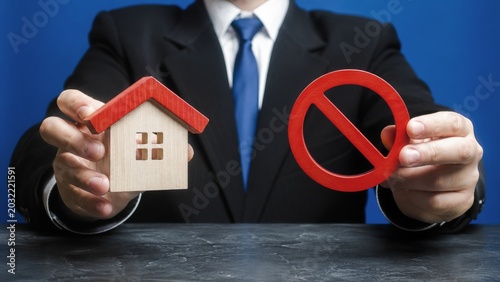 A businessman holds a model house in one hand and a 