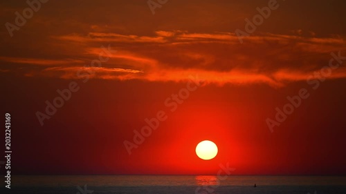Beautiful sunset over tranquil sea with vibrant red sky and reflections on water, cinematic 4K.