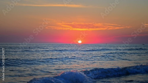 Dramatic sunset above tranquil sea with soft waves and warm reflections, cinematic 4K.