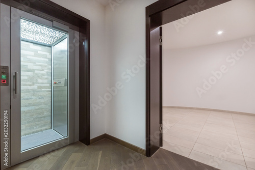 Modern design of the basement of a private house. A bright hall, a private elevator with a glass door.
