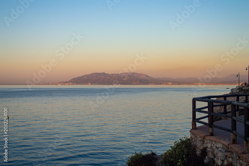 Sunrise over the sea in Rincon de la Victoria, Malaga, Spain, with golden light reflecting on calm waves along the coast.