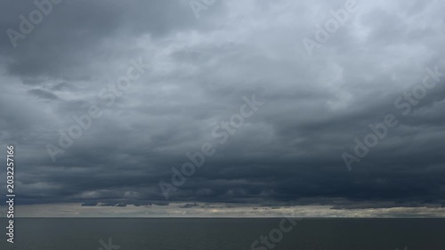 Video of a large lake with stormy clouds and occasional seagulls flying above a calm lake that is reflecting the sky
