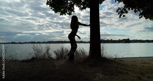 Silhouette of a Ballet Pose Graced by the Calm Water Under a Stunning Sunset Sky