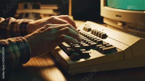 Hands typing on old computer keyboard in low light setting