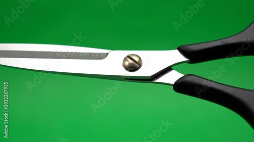 Close up of stainless steel scissors on vibrant green background
