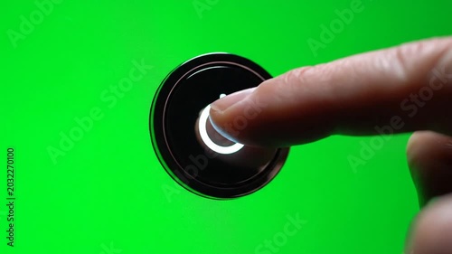 Finger presses illuminated power button against green background