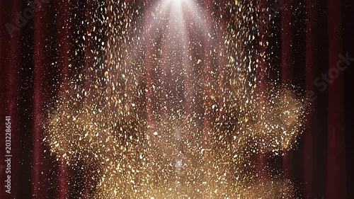Glittering golden confetti explodes upwards dramatically on a stage with a spotlight shining through dark red curtains.