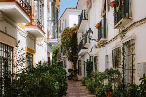 Fotografie Narrow street with traditional white buildings featuring wrought iron balconies