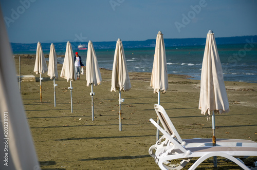 Fotografía Closed beach umbrellas and lounge chairs on empty sandy shore