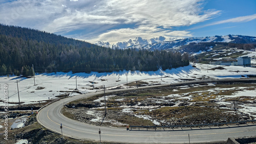 High angle view of a winding mountain road with patches of melting snow on the way to Hemu, Xinjiang. 