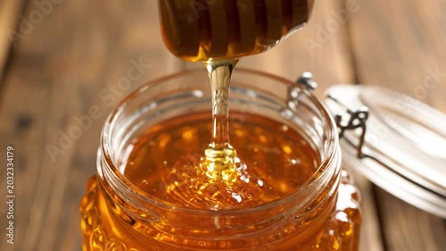 Golden Honey Dripping From Dipper Into Jar