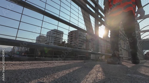 Construction Worker Walking Through Modern Urban Infrastructure at Sunset