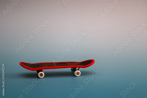 Two miniature skateboards with black griptape and bright red and yellow edges rest on a soft pale green gradient background. This high-angle view showcases the sleek fingerboard design, offering ample