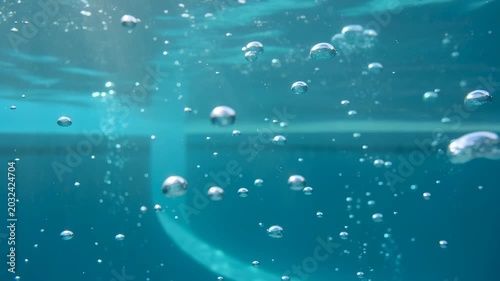 Bubbles rising in clear blue water with light reflections during a gentle underwater current