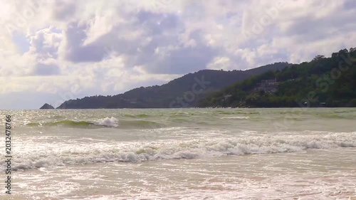 Tropical Patong Beach with strong waves dramatic dark clouds and clear water Thailand.