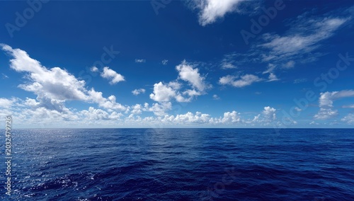 Vast ocean under a bright blue sky with scattered fluffy white clouds