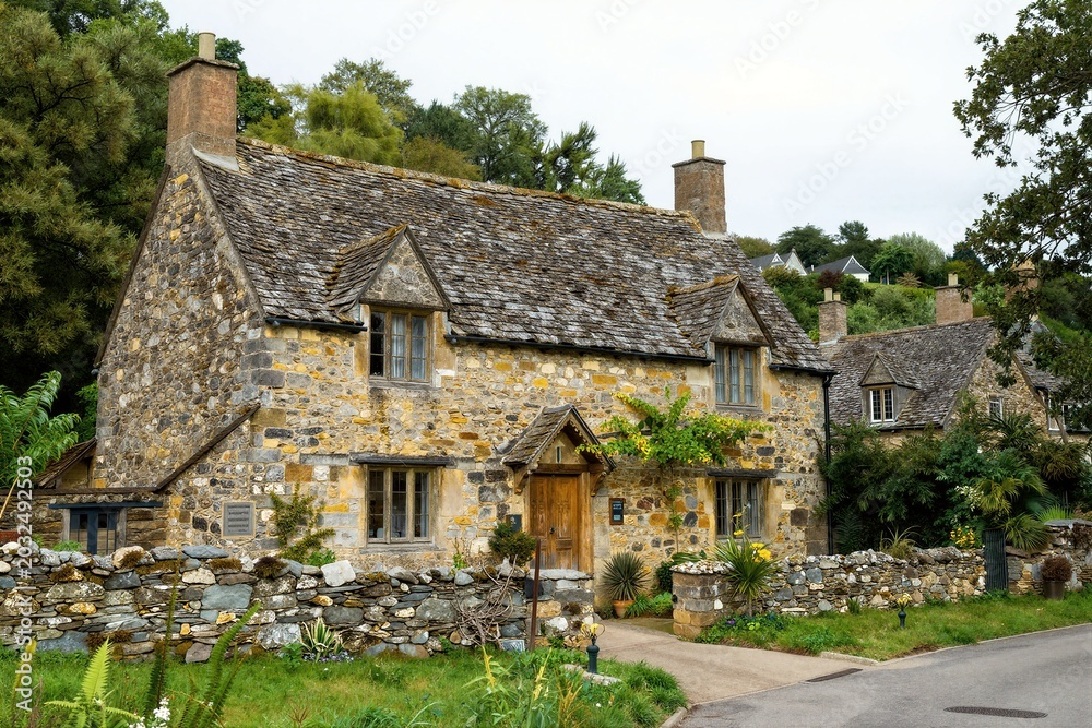 Fototapeta premium Stone cottage surrounded by stone wall in rural lane